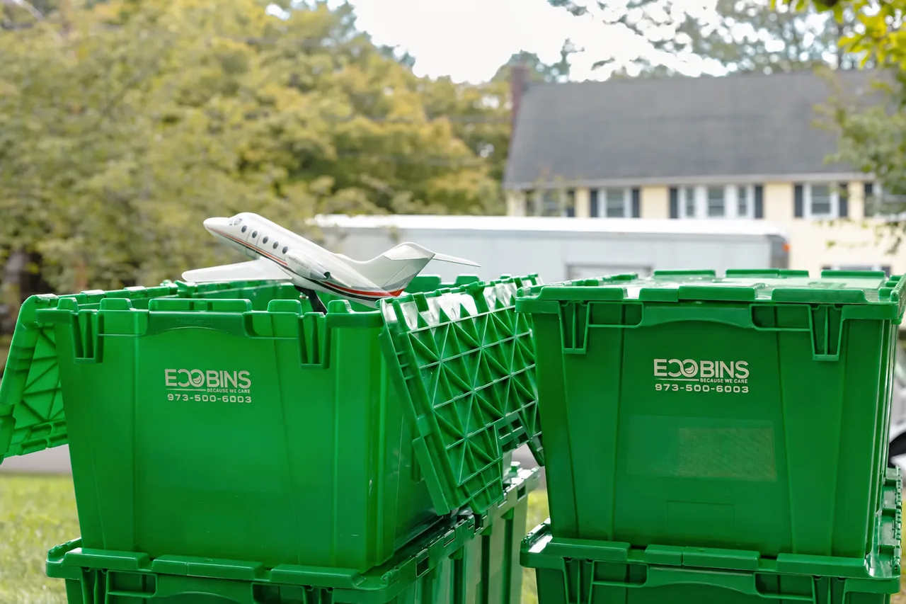 An open EcoBin holding household belongings beside a closed bin, showing the attached split lids